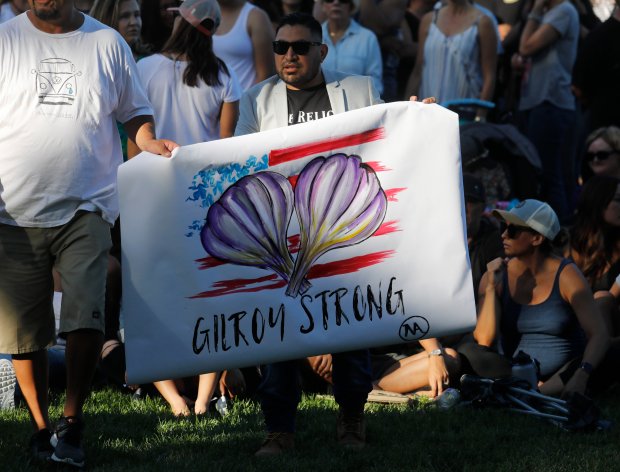 Artist Ignacio 'Nacho' Moya carries a sign he made during a vigil for the victims of the Gilroy Garlic Festival Shooting (Nhat V. Meyer/Bay Area News Group)